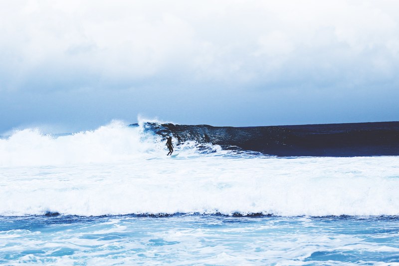 a distant surfer riding a rough ocean wave in west java, riding the rough waves 4k