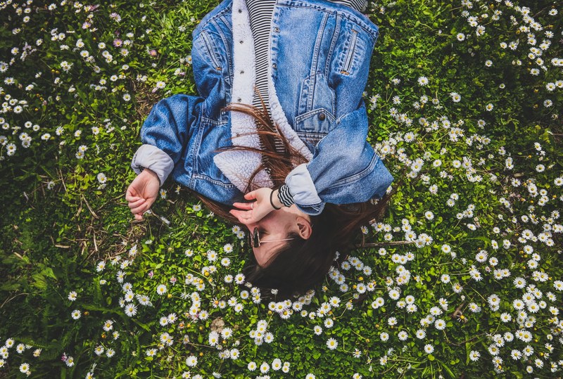 happy woman laying down in a field of wildflowers, laying down alone 4k