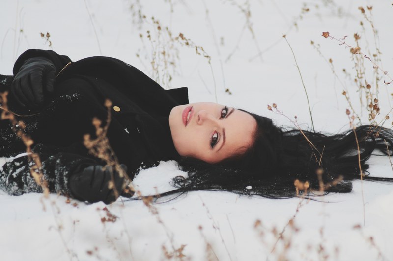 woman laying down in a field of snow alone, lying in snow 4k