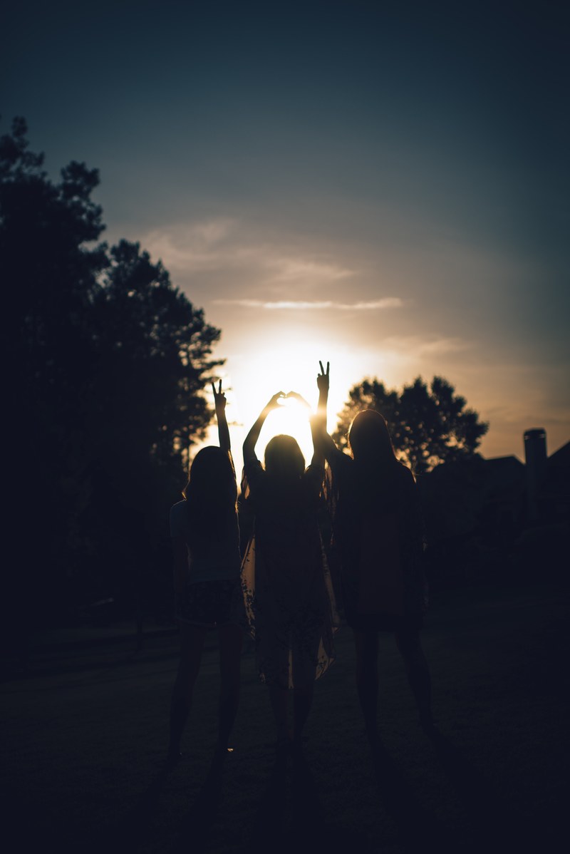 silhouette of three girls holding up peace signs and a heart hand sign during sunset, love and peace in the sunset 4k