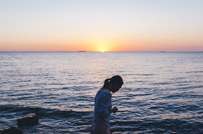 a woman in the ocean as the sun sets over the horizon brighton beach, soaking in the beauty of the earth 4k