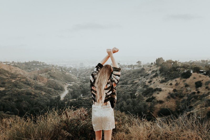 a woman holding her arms up in the sky on top of a mountain, _dancing in la 4k