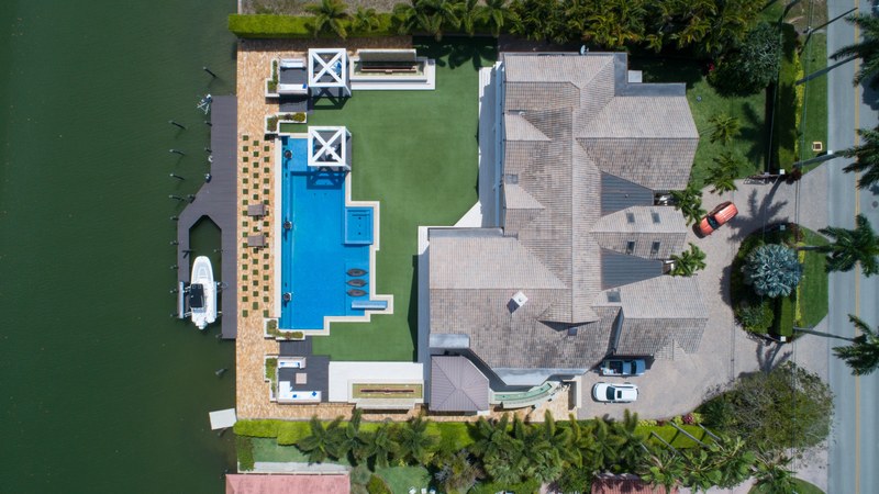 a drone shot of a mansion boat canal pool car and driveway in naples, port royal 4k
