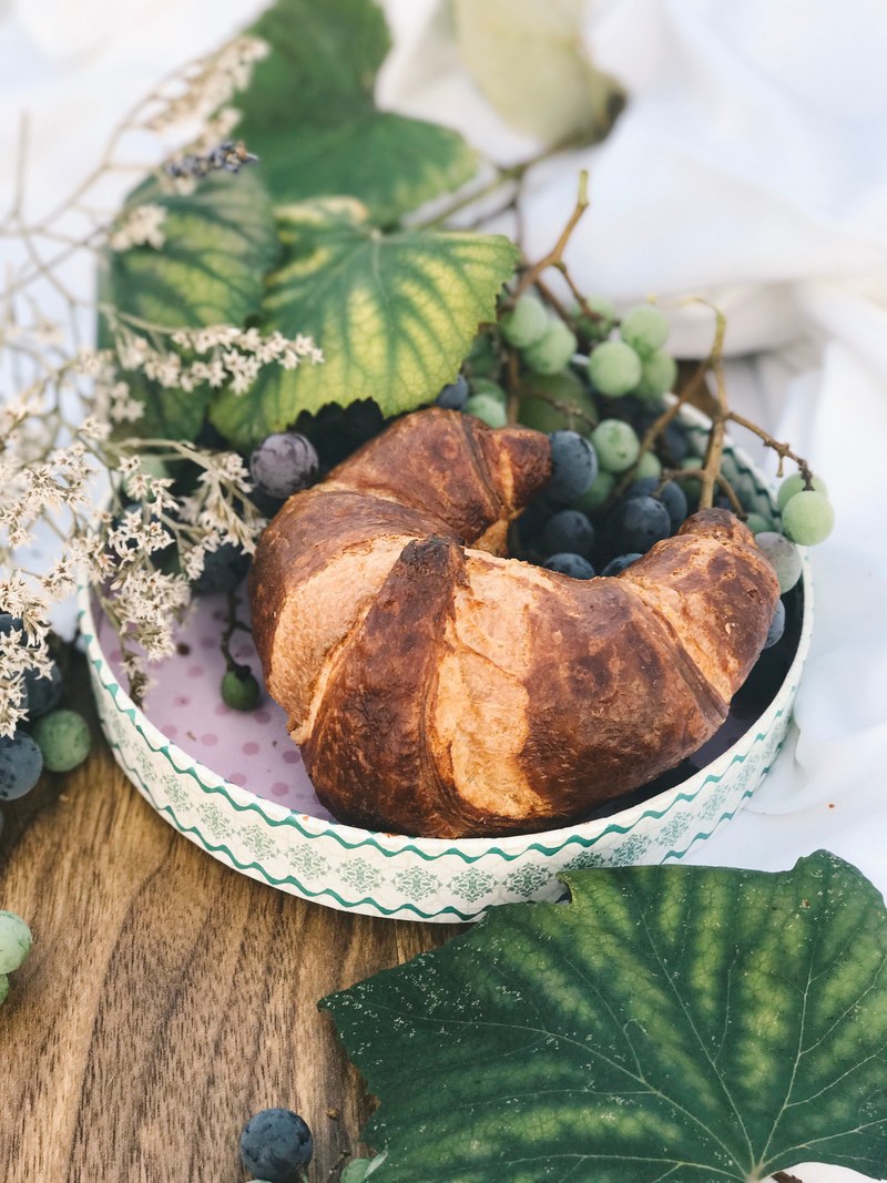 a croissant sitting in a plate with blueberries and grapes, _croissant blueberries grapes 4k