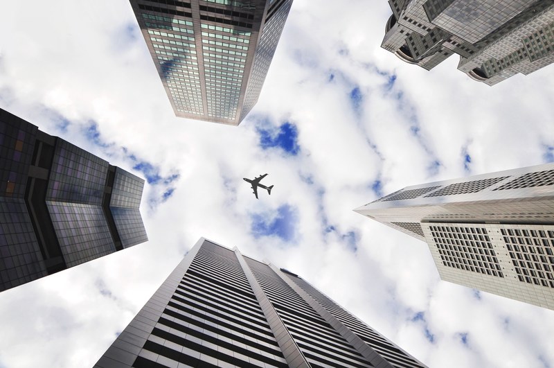 a low angle shot of an airplane flying over tall skyscrapers, plane over a city 4k