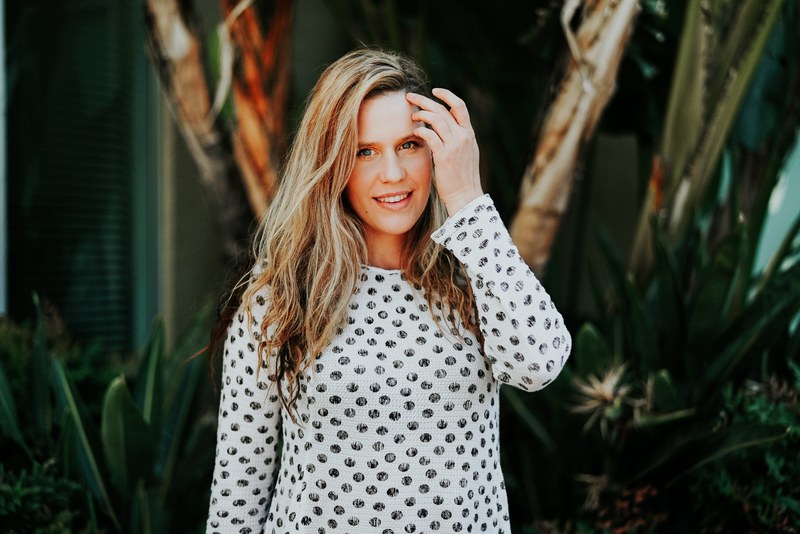 a woman in a polka dotted shirt touches her forehead in front of a blurry background, woman in polka dotted shirt 4k