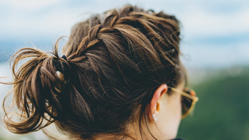 a woman with a braid in sunglasses faces away from the camera against a blue sky, woman with braid 4k