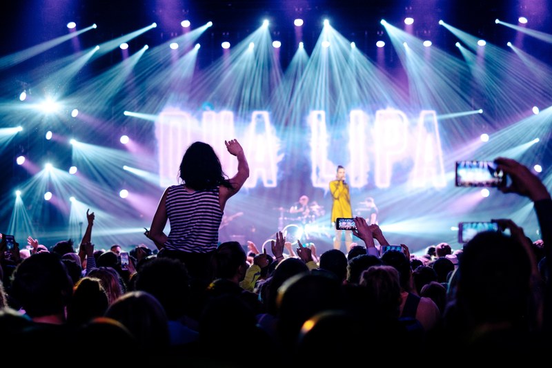 concert audience lifting up their hands and phones as a woman in a yellow dress performs on stage, fabulous concert with a singer in yellow dress 4k