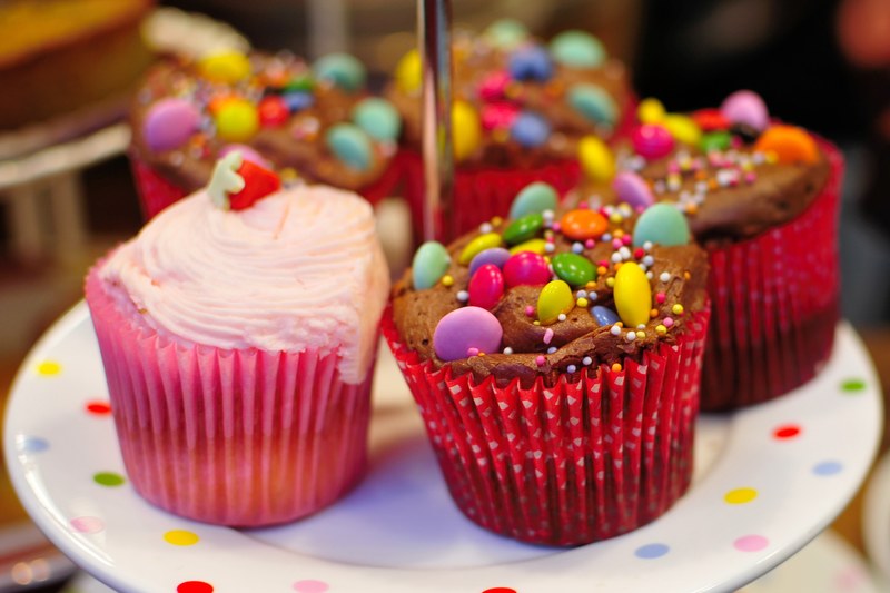 a plate with cupcakes topped with cream and candy, colorful candy cupcakes 4k
