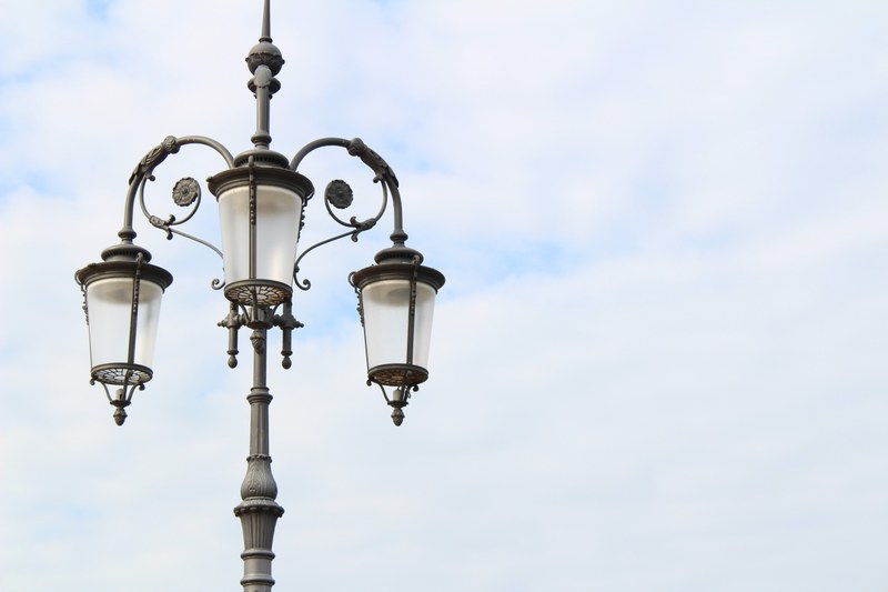black lamppost with ornate flower designs and three lanterns against a cloudy sky, lantern 4k