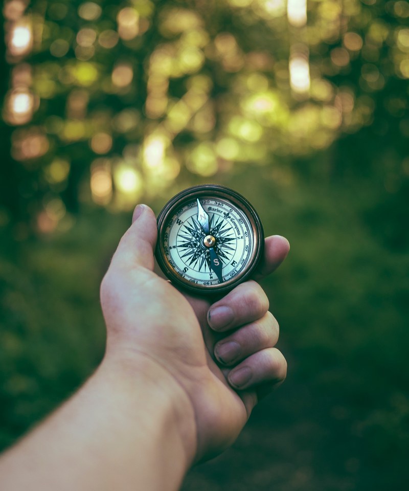 a persons hand holding and old fashioned compass in the wilderness, vintage compass in hand 4k