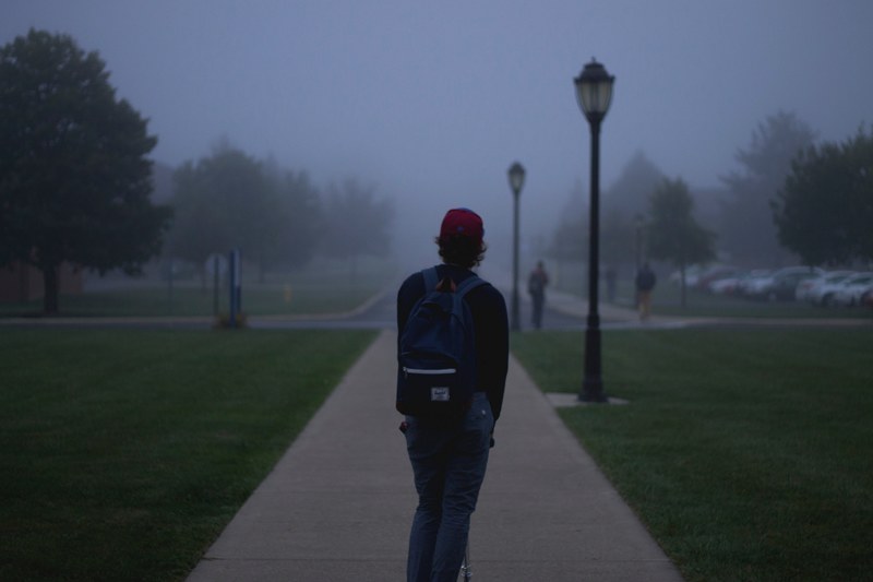 college student alone on a razor scooter on a foggy day, getting to class 4k