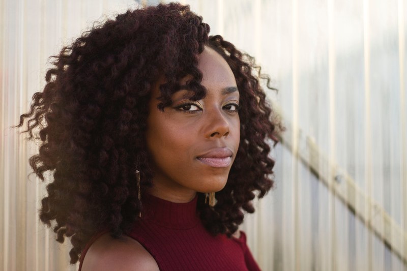 woman with curly hair looks confidently into camera, confident eye contact 4k