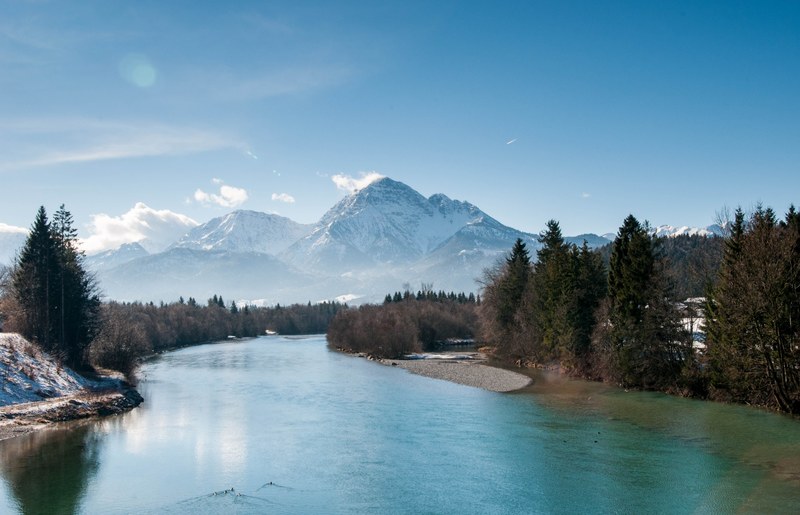 a scenic landscape with a bending river and snow capped mountains in the distance, beautiful river bend at the foot of a mountain 4k