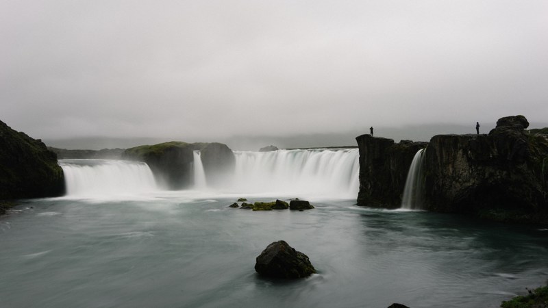 a gray image capturing two waterfalls streaming into a pool of water, multiple waterfalls in the same area 4k