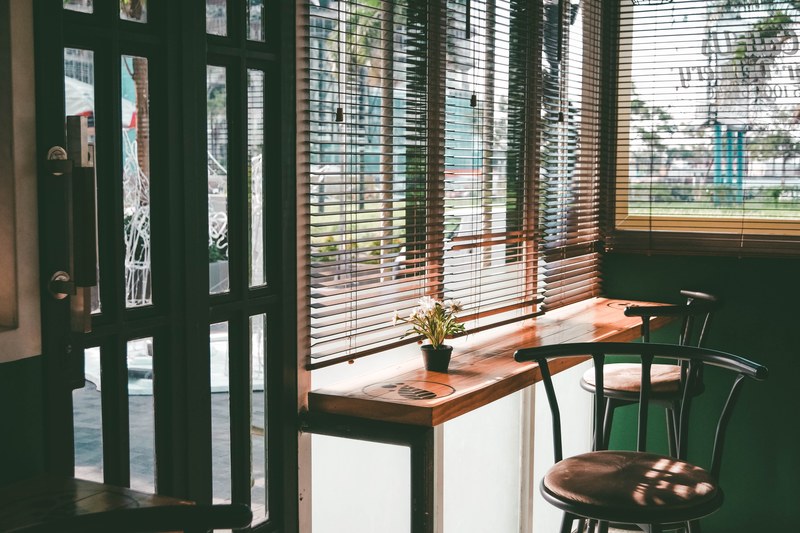 bar stools near a counter under blinded windows in the corner of a coffee shop, cozy coffee shop corner 4k