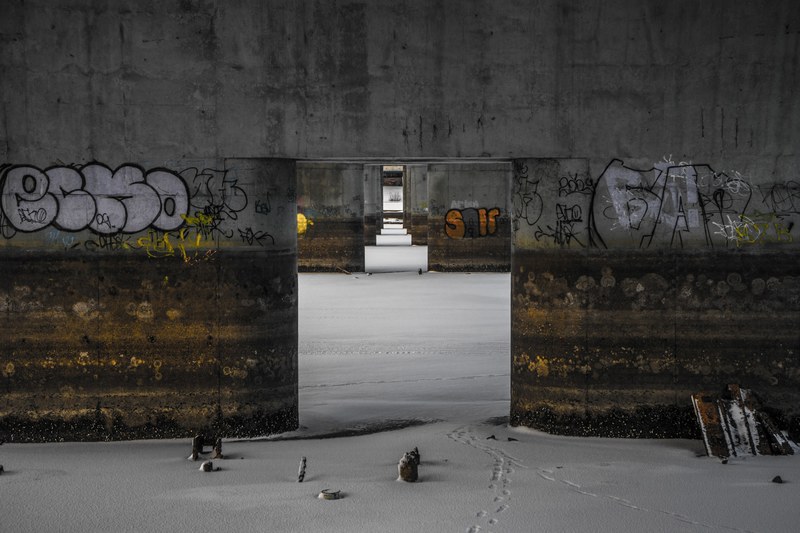 footprints in shallow snow lead though a large opening in a cement wall covered in graffiti, a long time ago in a place far far away 4k