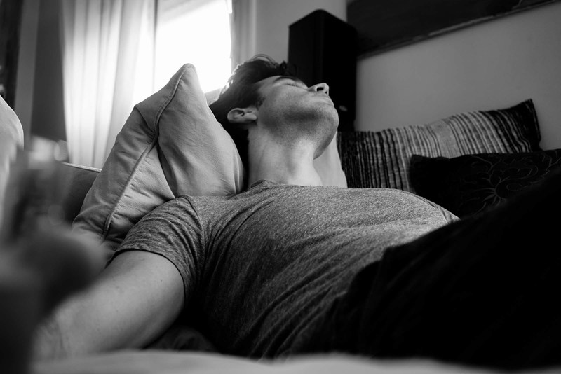 black and white shot of man in casual clothes sleeping and resting on sofa inside, man sleeping on sofa 4k