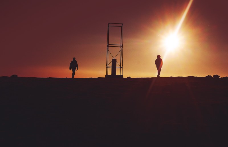 people walking in monte altissimo di nago are cast into silhouette against a terracotta and orange sunset, _gli uomini che si voltano 4k