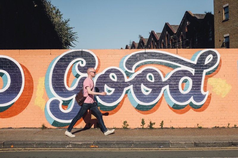 bald man walks in front of graffiti 4k