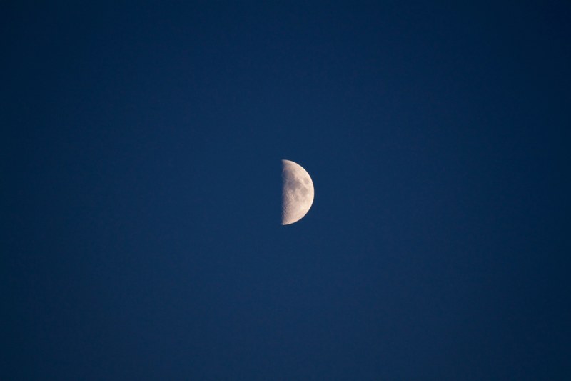 half moon with visible dark spots in the inky blue sky, half moon 4k