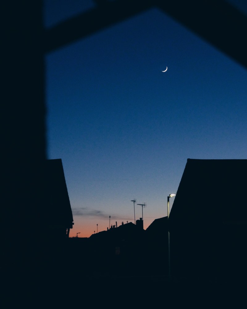 the crescent moon as seen through silhouetted houses in troon at night, _pancake day 4k