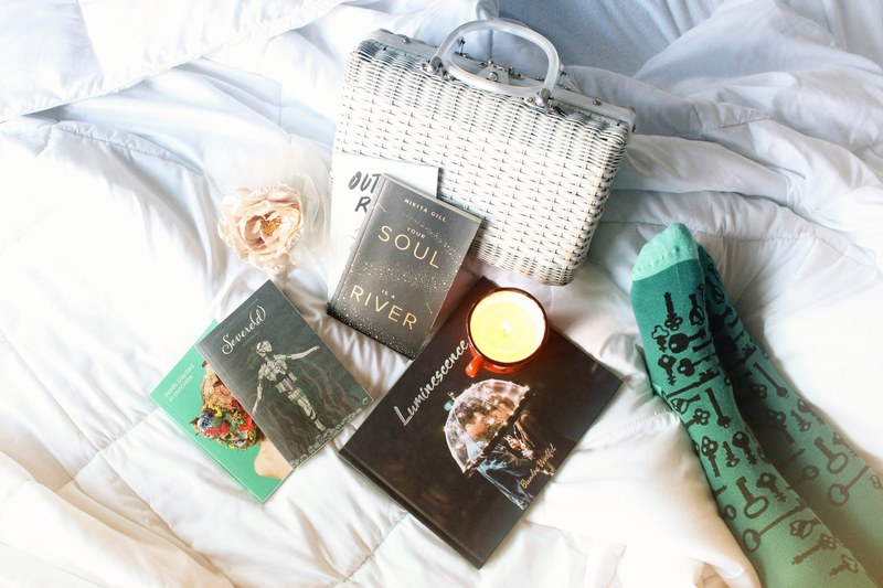 scattered books on a bed near feet and funky socks 4k