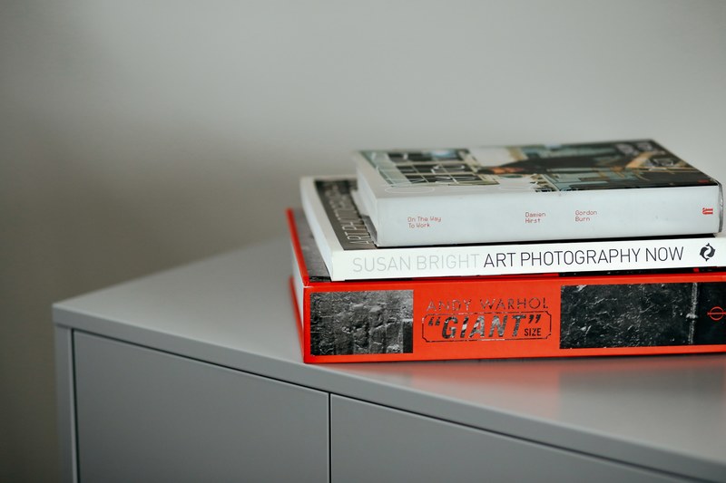 three art books stacked on a metal cabinet, art books stack 4k