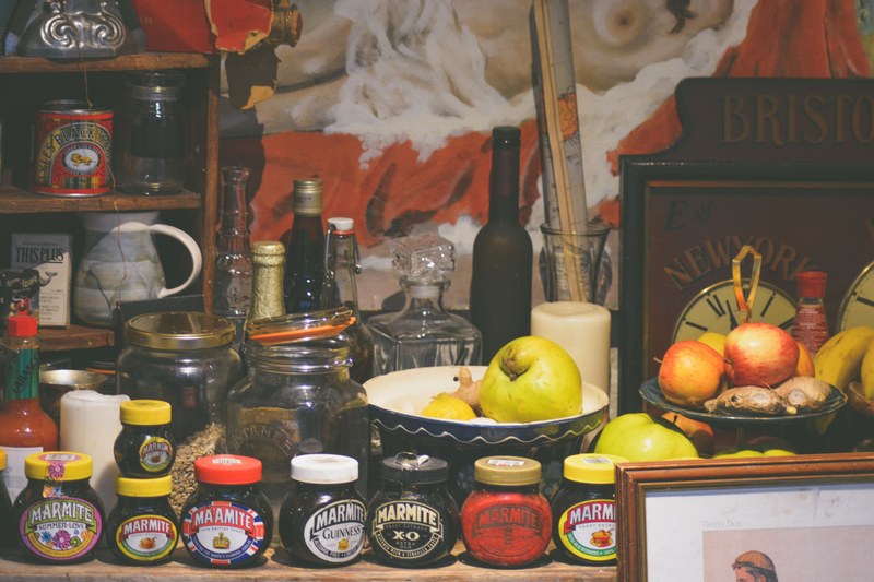 a busy shelf with a row of marmite jars fruit bowls empty jars and wine bottles, pantry shelf 4k