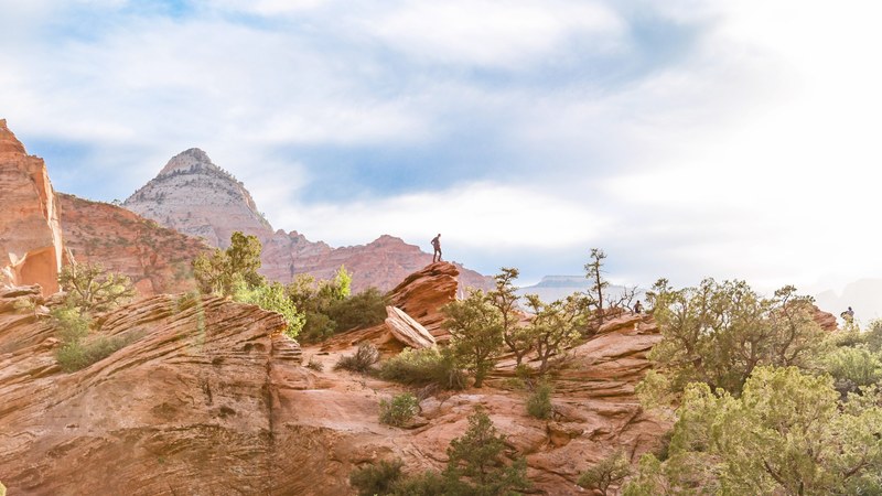 hiker stands on the edge of a rock in the desert landscape, exploring from above 4k
