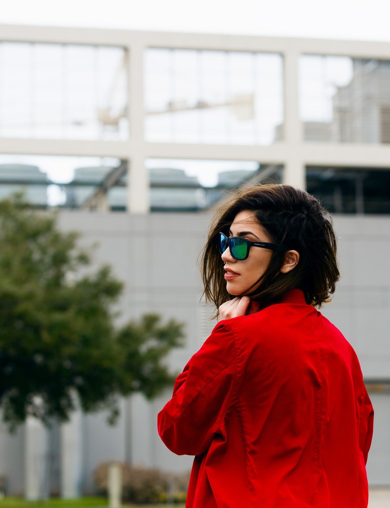 a woman in a red top is wearing sunglasses in front of a building, _woman red top sunglasses 4k
