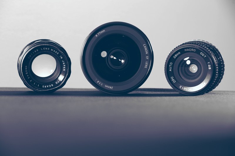 three camera lenses on their sides on a dark surface, three camera lenses 4k