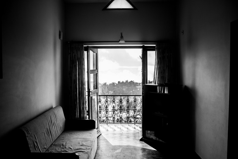 black and white shot of worn down sofa and balcony window with view from flat kodaikanal, balcony window kodaikanal 4k