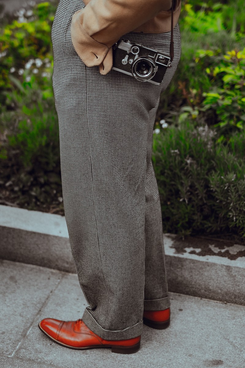a man in checkered pants and brown shoes with a vintage camera in lewis cubitt square, _baggy trousers 4k