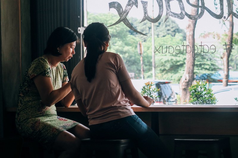 two women sitting and talking by a coffee shop window, women talking in a coffee shop 4k
