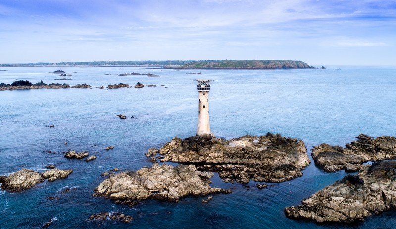 old lighthouse on a small rock island at la fort guernsey, hanois lighthouse on a clam day 4k