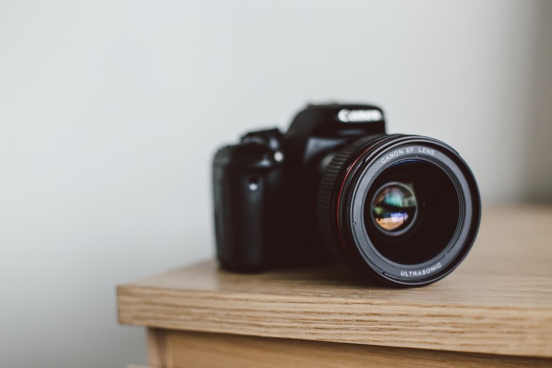 canon camera on the corner of a wooden table, canon camera on table 4k