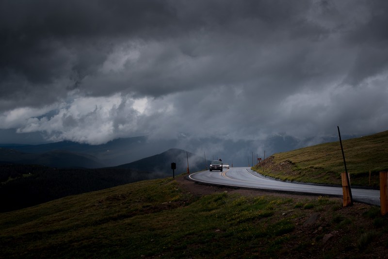 cars on a curve in a road along a green hill on a cloudy day, curve in hill road 4k