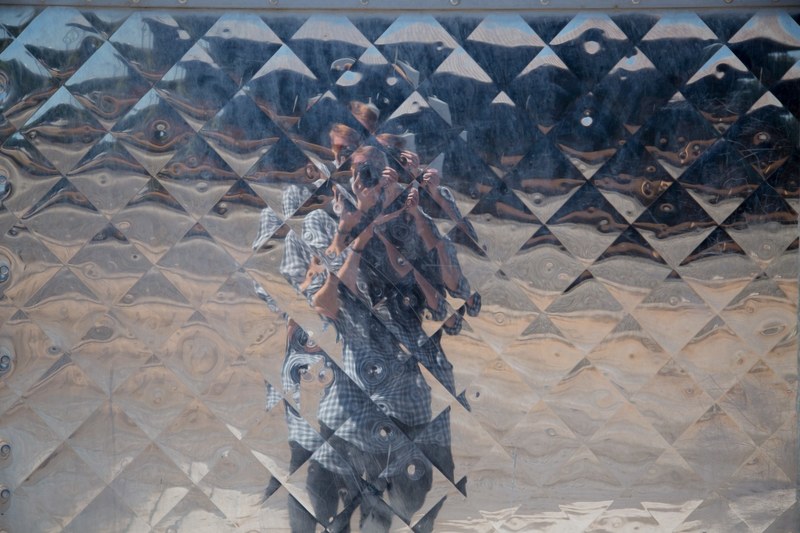 a distorted reflection of a photographer taking a photo of the reflective surface, geometric reflection pattern 4k
