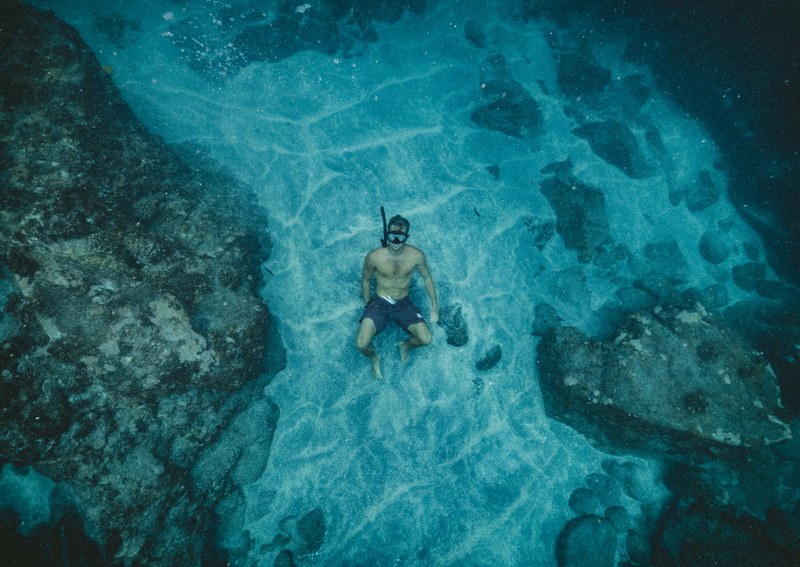 a man free diving in the sea surrounded by coral and rocks, the dive 4k