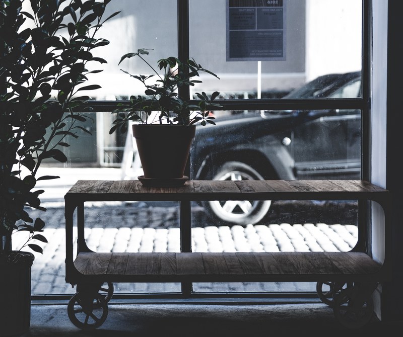 a pale shot of a coffee table on wheels with a potted plant on it next to a tall window, vintage wheeled coffee table 4k