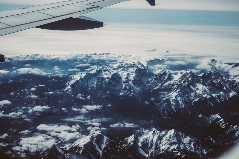 view of airplane wing crossing snowy mountains, airplane wing crosses snowy mountains 4k