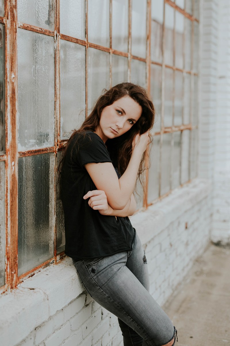 woman pouting and leaning against abandoned building windows, model pout 4k