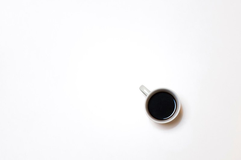 an overhead shot of a cup of coffee on a white surface, minimalist black coffee 4k