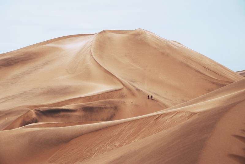 people take an extreme hike through the hot terrain of namib desert, hiking through sand dunes 4k