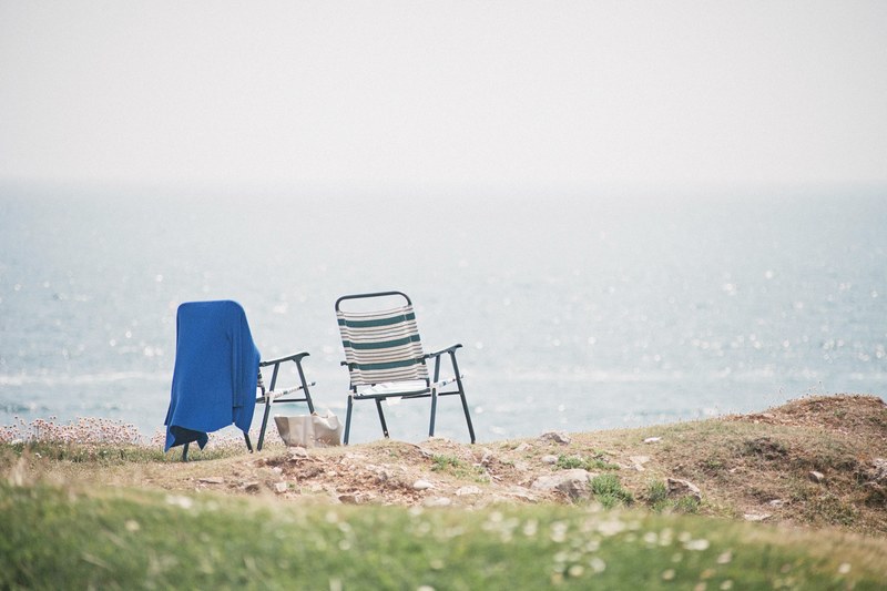 two folding chairs on the shore looking on the ocean, beach chairs towel sea 4k