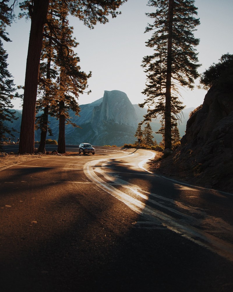 an suv driving on a curve in a mountain road in sunlight, driving through california during golden hour 4k