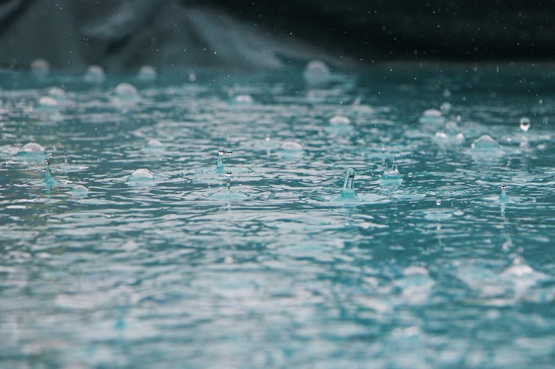 drops of rain splash and ripple into a blue sea of water in nederland, rain drops 4k