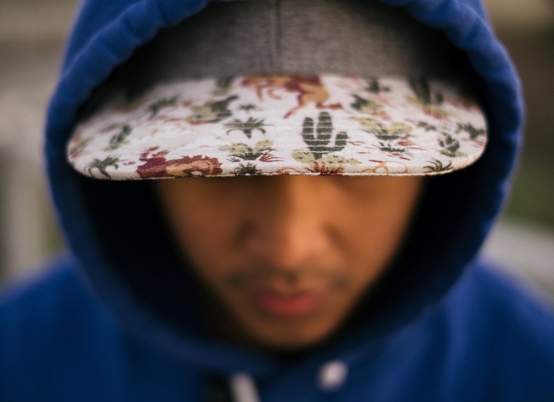a person in a baseball cap and blue hoodie leans forward displaying the patterned brim, baseball cap brim 4k
