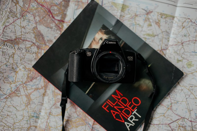 canon eos 500 camera without a lens on a film and video art magazine on top of a map of stoke on trent, canon without lens on map 4k